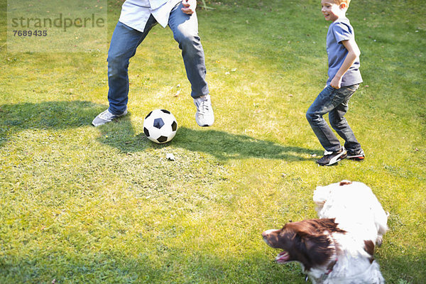 Junge spielt Fußball mit Hund im Freien