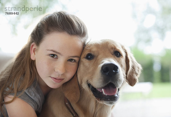 Mädchen umarmender Hund im Haus