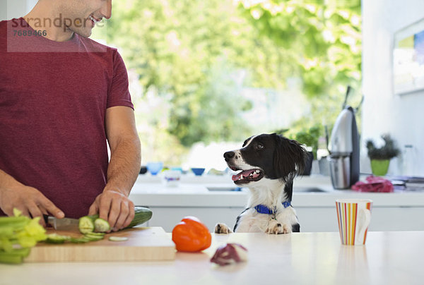 Mann kocht mit Hund in der Küche