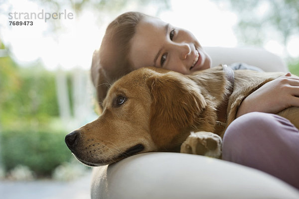 Mädchen entspannt mit Hund auf Sofa