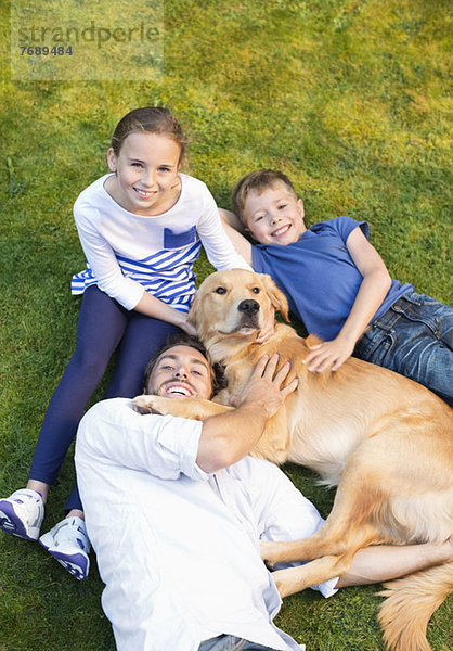 Familie entspannt mit Hund auf dem Rasen