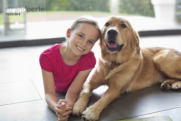 Lächelndes Mädchen entspannt mit Hund im Haus