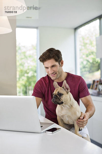 Mann mit Laptop und Hund auf dem Schoß