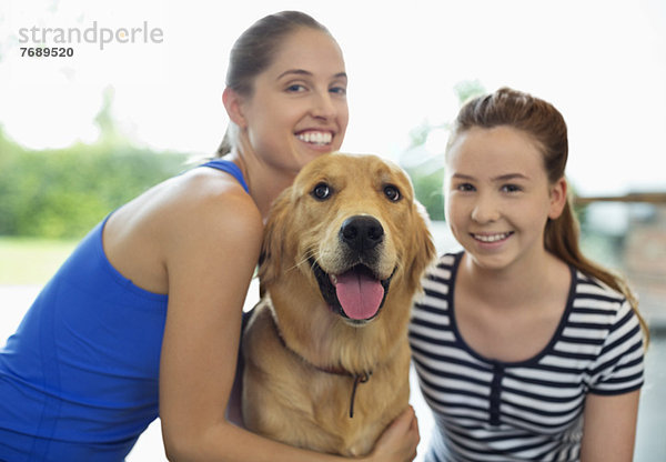 Mutter und Tochter lächeln mit Hund