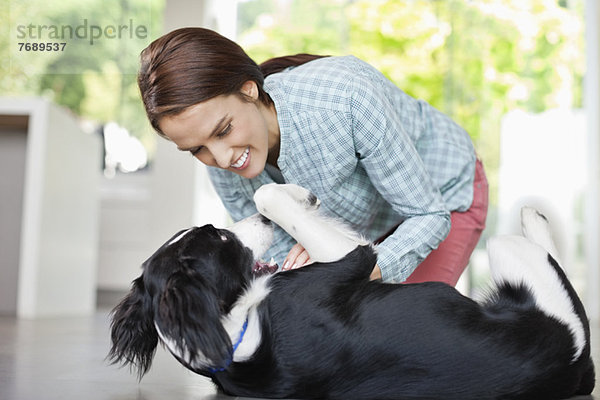 Lächelnde Frau spielt mit Hund