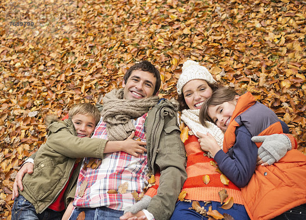 Lächelnde Familie im Herbstlaub liegend