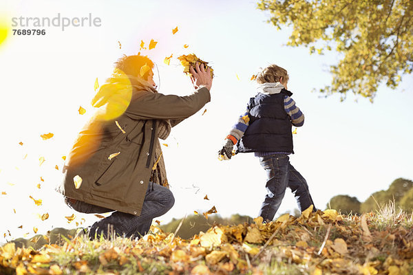 Vater und Sohn spielen im Herbstlaub