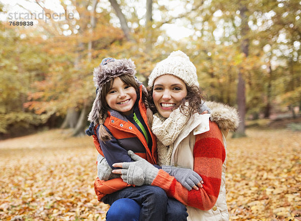 Mutter und Tochter lächeln im Herbstlaub