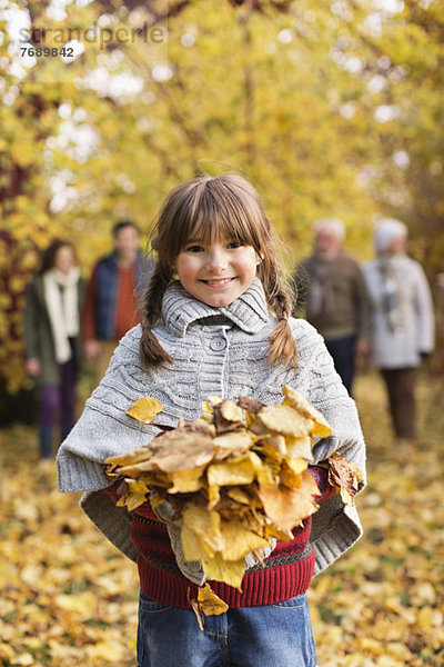 Lächelndes Mädchen spielt im Herbstlaub