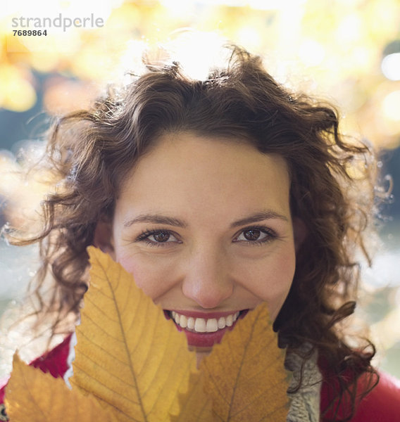 Lächelnde Frau mit Herbstblatt