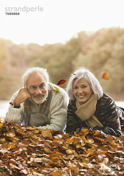 Älteres Paar im Herbstlaub liegend