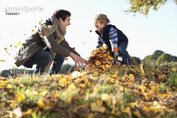 Vater und Sohn spielen im Herbstlaub