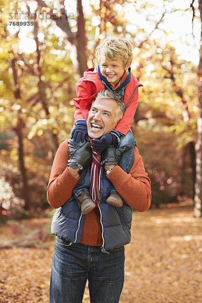 Älterer Mann mit Enkel auf den Schultern im Park