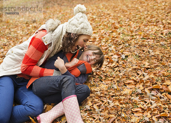 Mutter und Tochter spielen im Herbstlaub