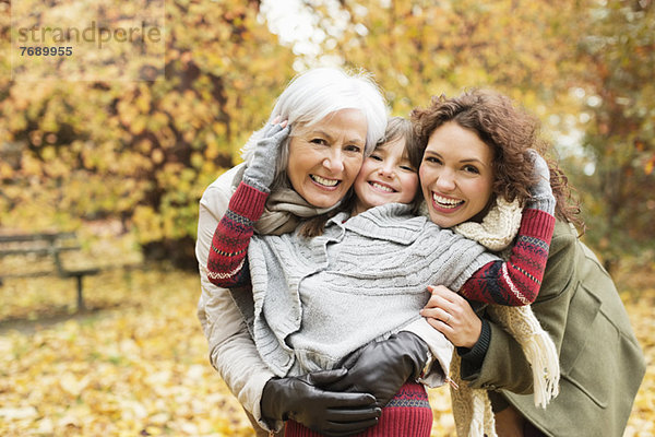 Drei Generationen von Frauen lächeln im Park