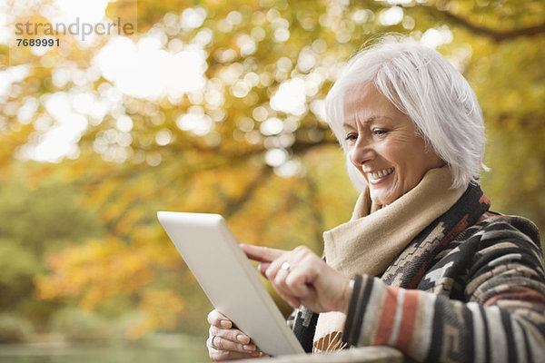 Ältere Frau mit Tablet-Computer im Park