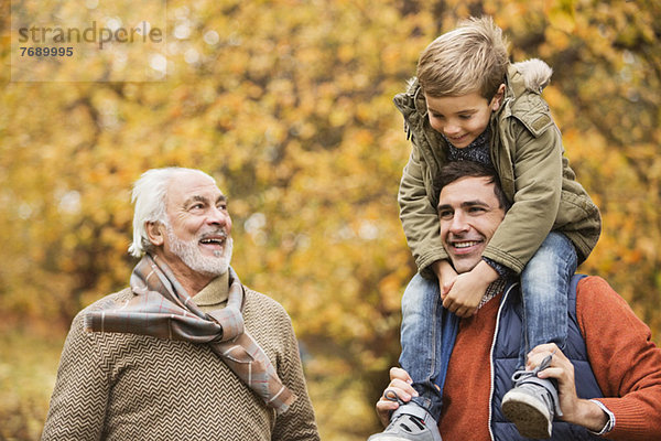 Drei Generationen von Männern lächeln im Park