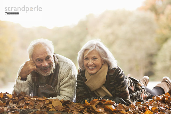 Älteres Paar im Herbstlaub liegend