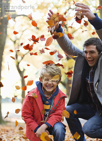 Vater und Sohn spielen im Herbstlaub