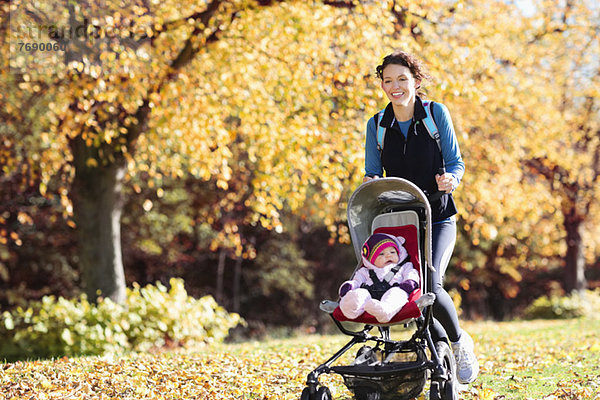 Frau beim Laufen mit Kinderwagen im Park