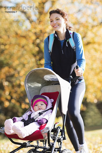 Frau beim Laufen mit Kinderwagen im Park