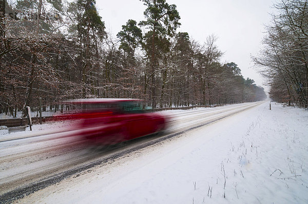 Verschneite Landstraße im Winter mit schnell fahrendem PKW  Wischeffekt