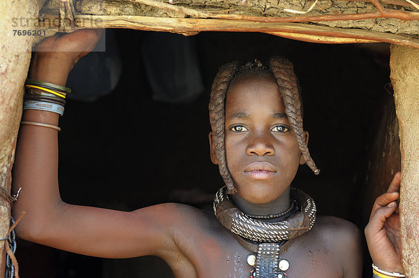 Himba-Mädchen mit zwei geflochtenen Zöpfen und Schmuck  Portrait  Himba-Hütte  Himba-Dorf