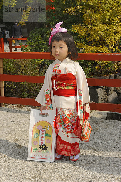 Mädchen im festlichen Kimono beim Shichi-go-san  Sieben-fünf-drei Fest  hält eine typische Tüte  Chitose-ame  in der sich Zuckerstangen befinden  Shimogamo Jinja  Kyoto  Japan  Ostasien  Asien