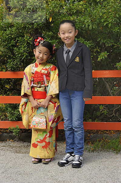 Ein japanisches Mädchen im Kimono und ein japanisches Mädchen in westlicher Kleidung  Kyoto  Japan  Ostasien  Asien