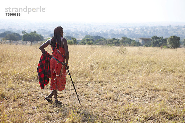 Stolzer Massai in traditioneller Kleidung blickt über die Savanne