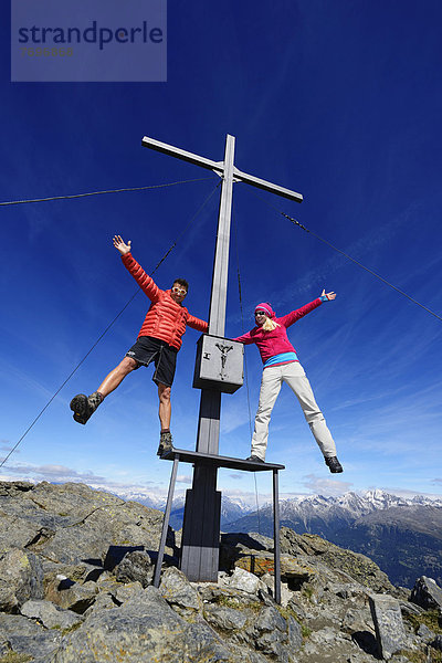 Wanderer auf dem Gipfelkreuz auf dem Gipfel Böses Weibele in der Defregger-Gruppe  Karnische Dolomiten  Oberlienz  Pustertal  Osttirol  Österreich  Europa
