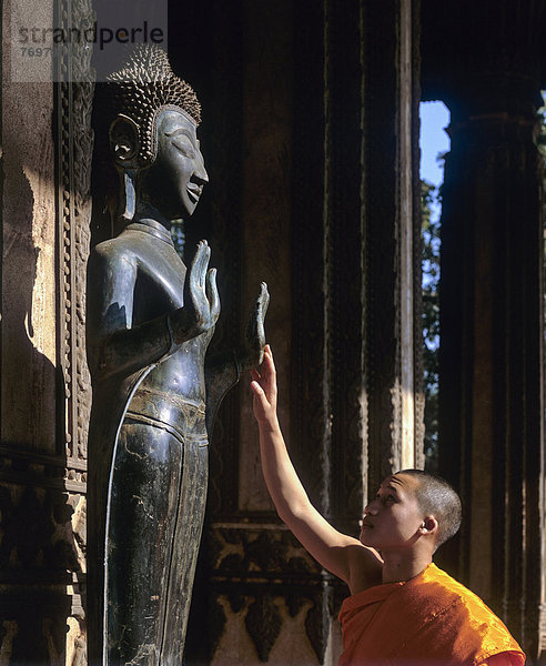 Mönch berührt Buddha-Statue  Altar des Smaragd-Buddha  Wat Ho Prakeo  Ho Phra Keo Tempel  Nationalmuseum