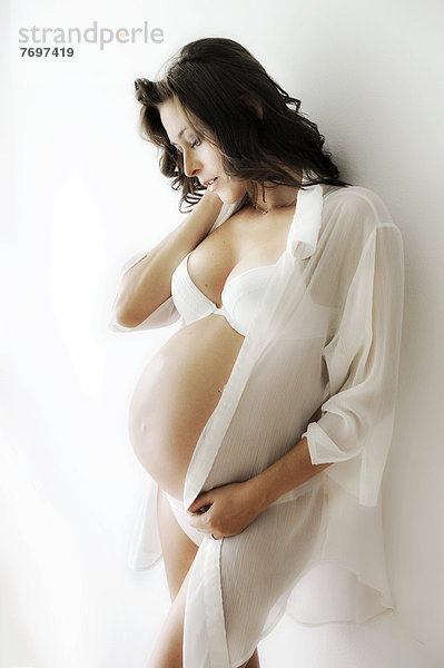 Schwangere Frau mit Schwangerschaftsbauch in Unterwäsche und Bluse