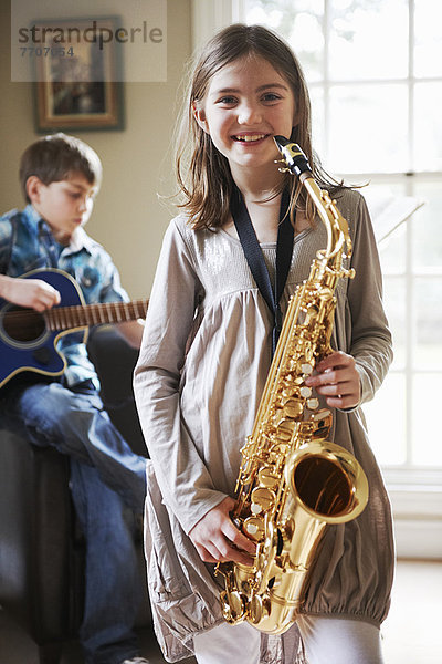 Lächelndes Mädchen spielt Saxophon