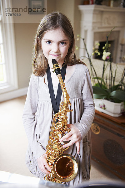 Lächelndes Mädchen spielt Saxophon