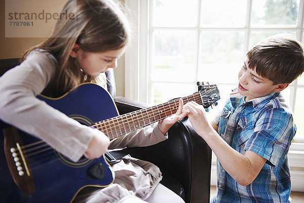 Junge hilft Mädchen Gitarre spielen