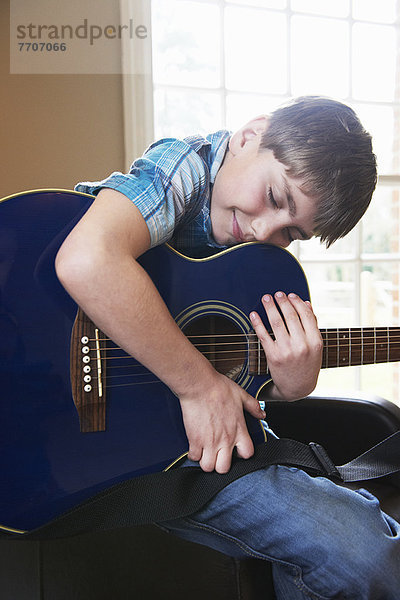 Lächelnder Junge umarmt Gitarre