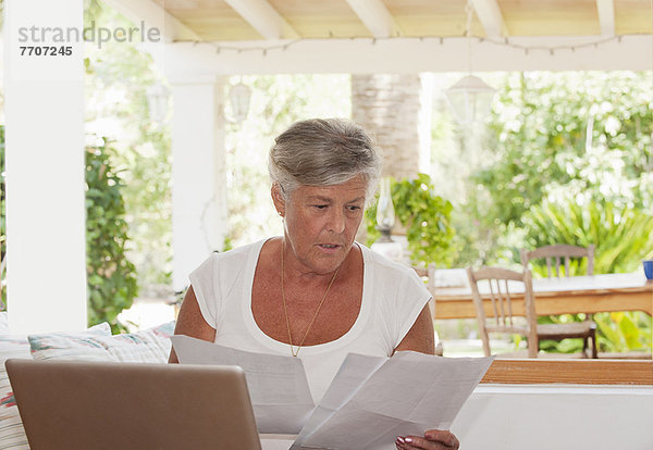 Ältere Frau bezahlt Rechnungen auf dem Laptop