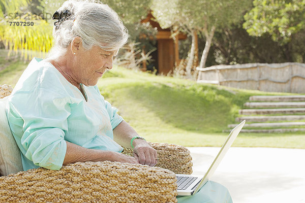 Ältere Frau mit Laptop im Freien