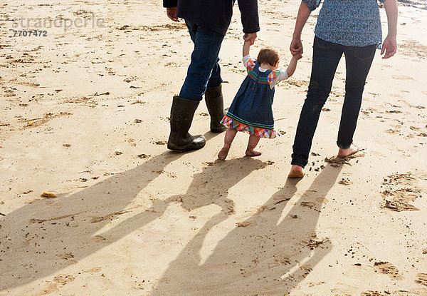 Paar hilft Kleinkind Mädchen laufen am Strand