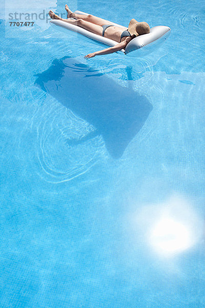 Frau auf dem Floß im Schwimmbad liegend