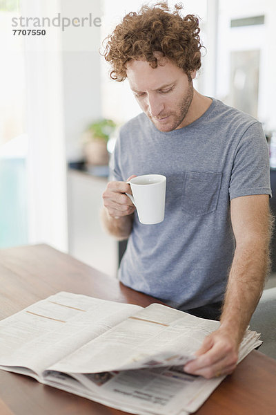 Mann liest Zeitung beim Frühstück