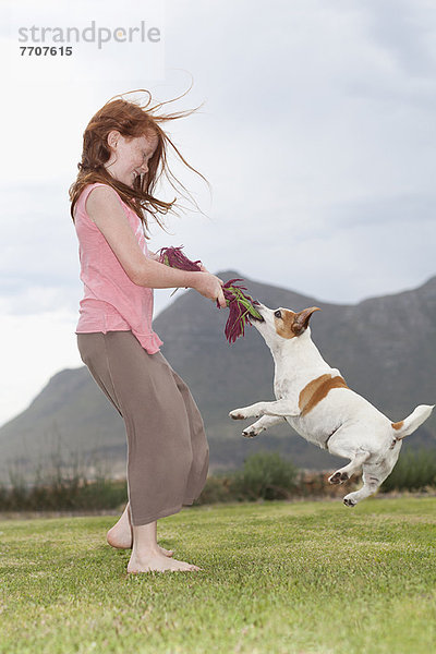 Mädchen spielt mit Hund im Gras