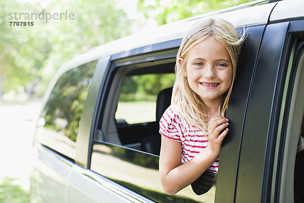 Lächelndes Mädchen im Autofenster stehend