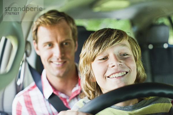 Junge fährt Auto auf Vaters Schoß