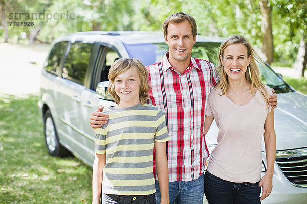 Familie lächelt zusammen mit dem Auto