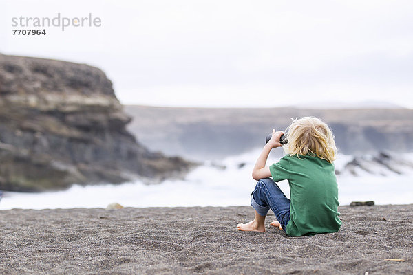 Junge mit Fernglas am Strand