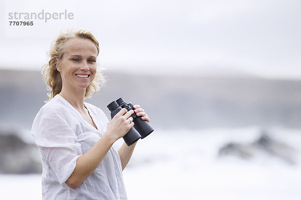 Frau mit Fernglas am Strand