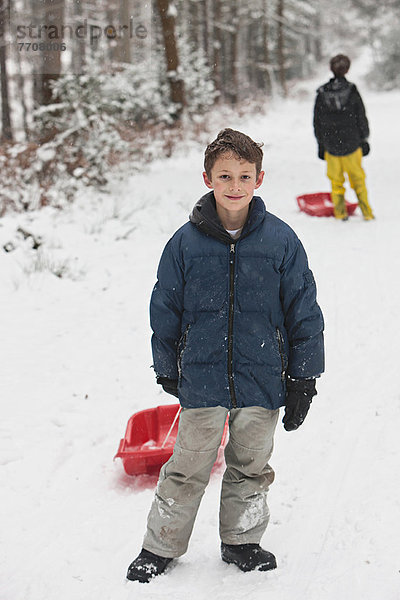 Junge hält Schlitten auf verschneiter Piste