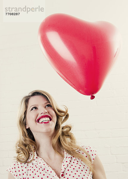 Lächelnde Frau mit herzförmigem Ballon